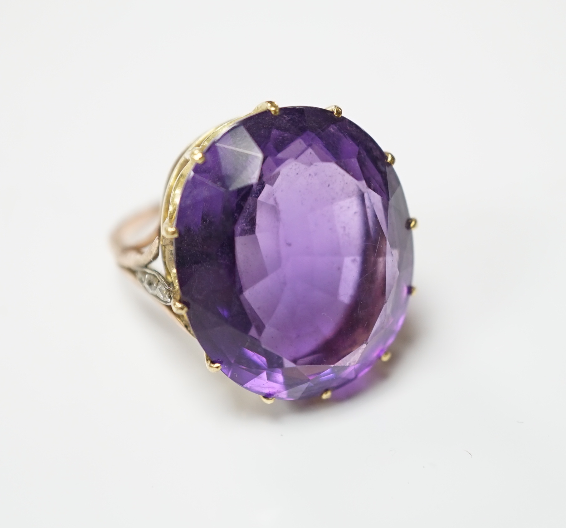 A yellow metal and oval cut amethyst set dress ring, with diamond chip set shoulders, size O, gross weight 10.6 grams.